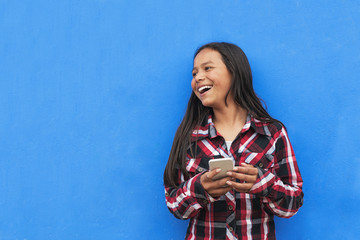 Portrait of beautiful latino girl using the mobile in the street.
