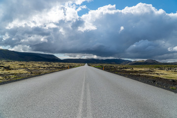 Empty, endless, straight street through the volcanic rocks in Iceland