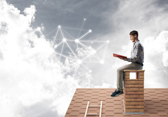 Man on brick roof reading book and concept of social connection