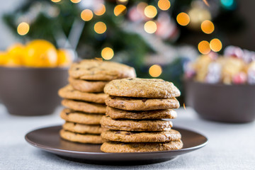 freshly baked chocolate chip cookies on a table with blurred christmas tree background.