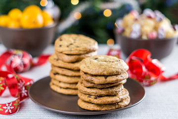 freshly baked chocolate chip cookies on a table with blurred christmas tree background.