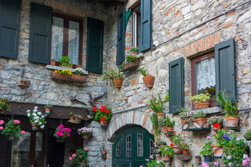 Many flower pots are hunging on the wall in a cozy yard