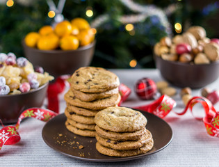 freshly baked chocolate chip cookies on a table with blurred christmas tree background.