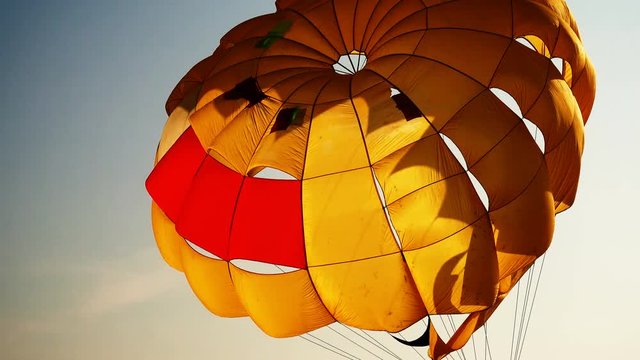 Parachute dome for parasail against the sky. It is illuminated by the rays of the setting sun. Water sports on the beach.