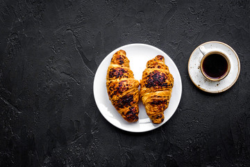 Light breakfast. Small cup of black coffee and croissant on black background top view copyspace
