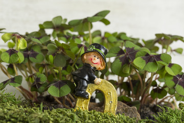 Schornsteinfeger auf goldenem Hufeisen vor Glücksklee