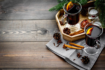 Warm mulled wine with citrus and spices for winter evening near spruce branch on dark wooden background copyspace