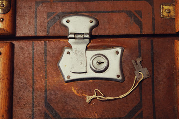 Fragment of old suitcase with closed clock and key