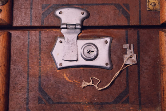 Fragment of old suitcase with closed clock and key