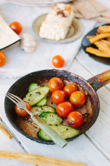 Roasted cherry tomatoes and cucumbers in frying pan.
