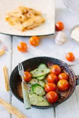 Frying pan with roasted cherry tomatoes and cucumbers.