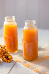 Healthy drink - sea buckthorn juice in a glass bottle over wooden table.