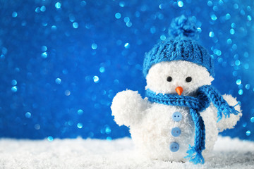 Small snowman toy on blue lights background