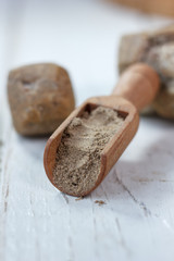Asafoetida spice in wooden scoop on table.