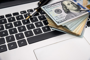 Pen and dollar banknote on keyboard, close up