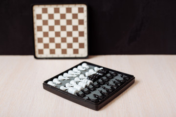 Chess and checkers on a wooden table and black background.