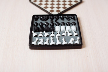 Chess and checkers on a wooden table and black background.