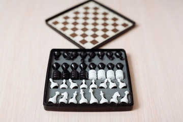 Chess and checkers on a wooden table and black background.