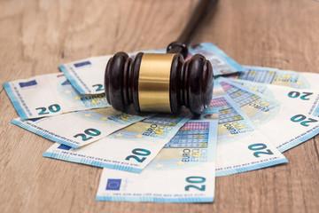 Wooden gavel with 20 euro banknotes on desk