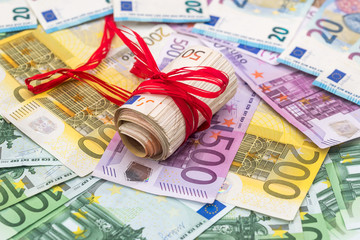 large pile of euro money with red ribbon