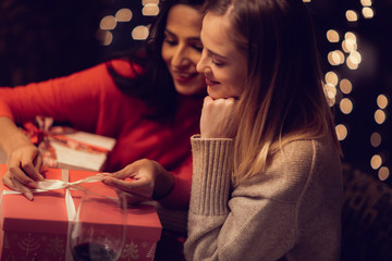 Two adolescent women going through the menue  in a fancy restaurant, while drinking a glass of red wine and laughing and talking, maybe gossiping
