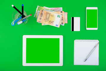 worktop top view. white tablet and smartphone with a blank screen, money, credit card, notepad with pen and pen  organiser