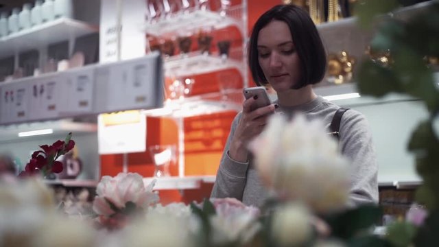 Young woman taking photo using smartphone in store with household products