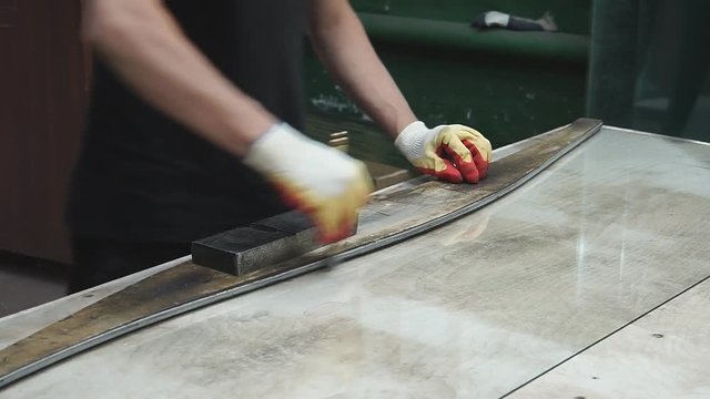 Cutting glass by glass cutter. Man's hands with gloves holding glass cutter.