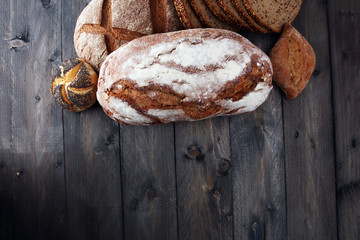 Different kinds of bread and bread rolls on wooden table. Kitchen or bakery poster design