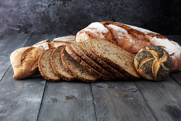 Different kinds of bread and bread rolls on wooden table. Kitchen or bakery poster design