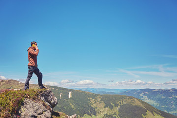Naklejka na ściany i meble Tourist a taking selfie on peak above mountain valley with sunrise and fog