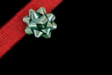 A red ribbon with a bow lies across the black background. Background for a postcard, frame.