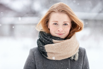 Beauty portrait natural looking young adorable redhead girl wearing knitted scarf grey coat on blurred winter background