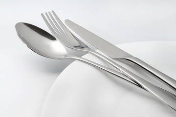 Spoon, fork and knife on white empty plate