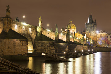 Fototapeta na wymiar Night snowy Prague Old Town with Bridge Tower and St. Francis of Assisi Cathedral and Charles Bridge with its baroque Statues, Czech republic