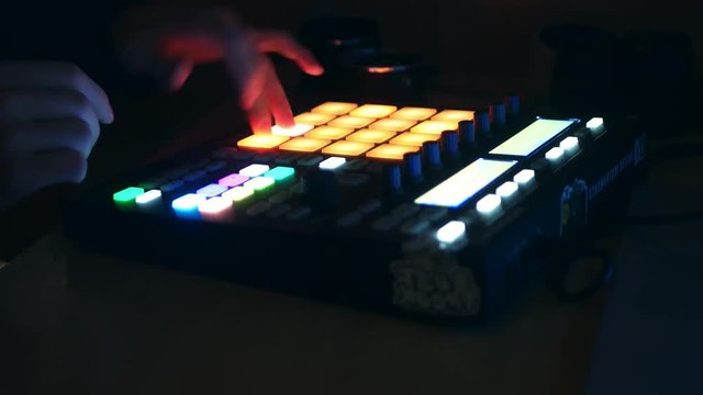 dj adjusting audio setting on the audio controller drum machine and playing music in the club