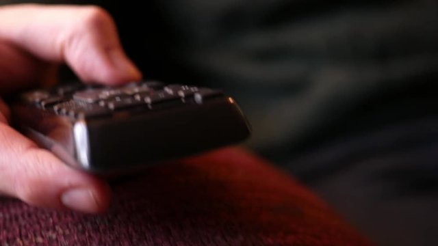 Man adjusts television channels from his remote control