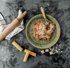 Italian cannelloni dish with meat in tomato sauce and parmesan on a concrete background - 185939877