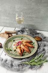 King prawns on a grill on a green plate and a glass of white wine on a gray concrete background - 185939897