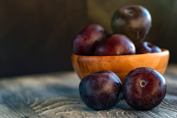 Garden plums in bowl on wooden table