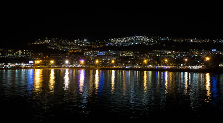 Fototapeta na wymiar Night photography of the city with blue and yellow lights reflecting in the ocean. Puerto Rico, Gran Canaria, Spain.