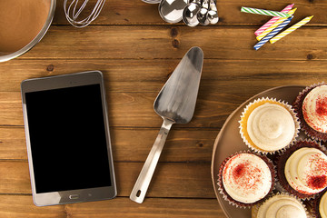 Cooking cupcake background with a digital tablet on wooden table. View from above.
