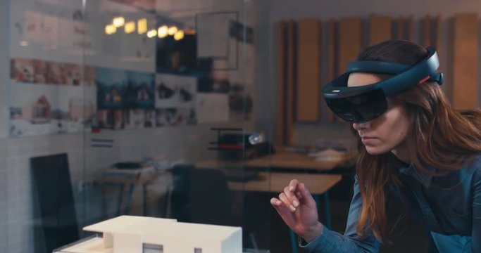 Caucasian female professional architect using augmented reality AR hololens headset to work on a house project. 4K UHD RAW edited footage