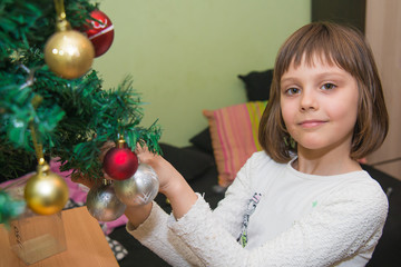 The girl decorates the New Year's tree