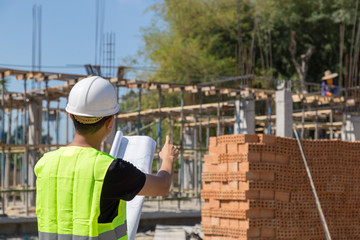 Naklejka na ściany i meble Engineers wear a helmet and holding construction plan monitoring the construction area.