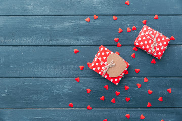 Fototapeta premium Top view of gift box with and red hearts decorations on Valentines day over wooden background