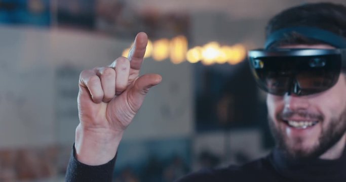 CU young adult Caucasian male using holographic augmented reality glasses in trendy office. Future concept. 4K UHD RAW edited footage 
