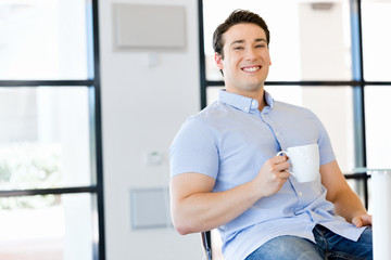 Obraz premium Young businessman in office with a mug