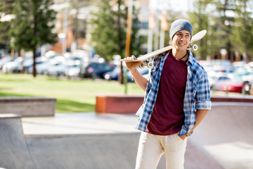 Teenage boy with skateboard standing outdoors