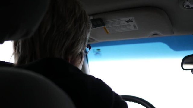 Rear view of woman talking to herself in a car while she drives